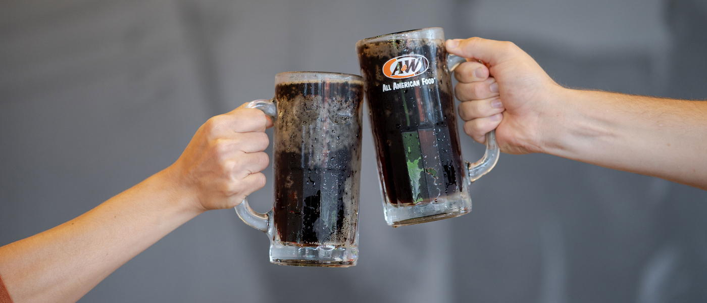 Two people toasting with mugs of A&W Root Beer